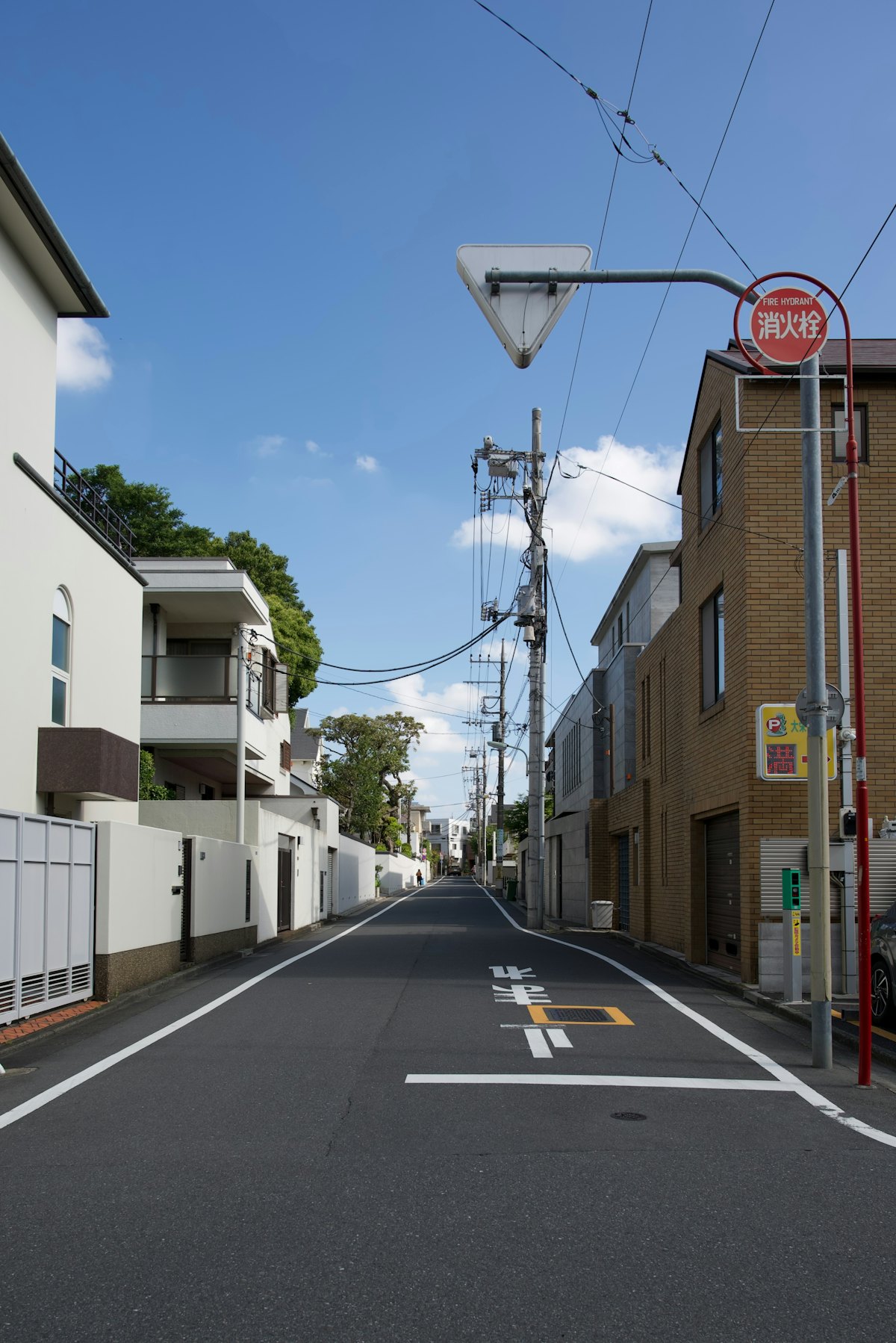 青空の下、家が並ぶ日本の住宅街の道(イメージ写真)